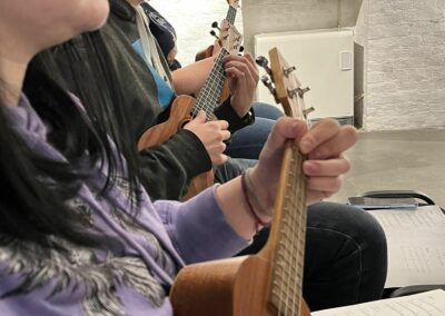 Uczestnicy zajęć muzycznych grają na ukulele
