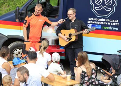 kucharz maciej gra na gitarze, ratownik medyczny trzyma mu mikrofon