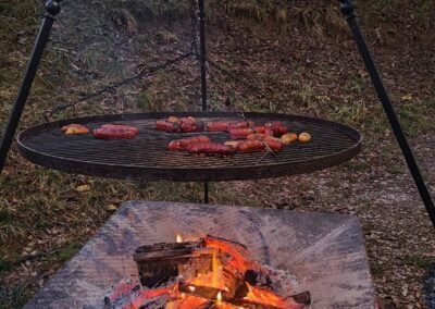 nad ogniskiem pieczą się kiełbaski na grillu