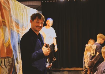 Pan uśmiecha się na tle płachty z teatrzyku